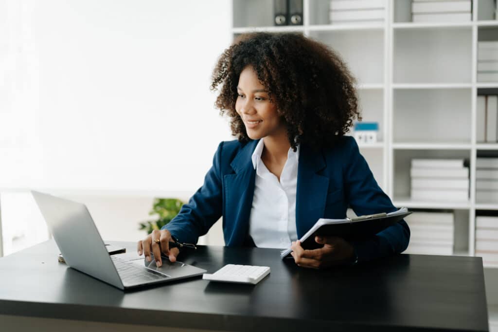 Business professional working on a laptop and reviewing documents, representing users benefiting from workflow automation